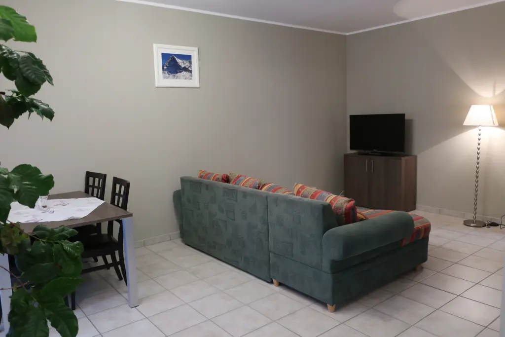 Wohnzimmer mit Sofa, Fernseher und Esstisch