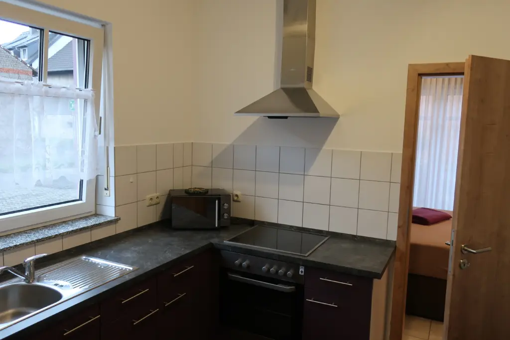 Kleine Küche mit Herd, Dunstabzugshaube und Spüle