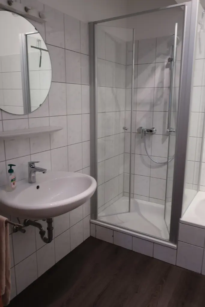 Badezimmer mit Waschbecken, Spiegel und Dusche