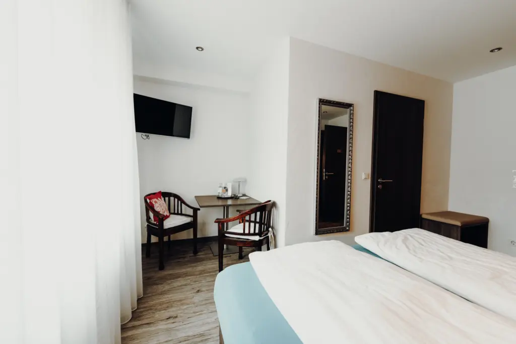 Helles Zimmer mit Bett, Schreibtisch und Spiegel