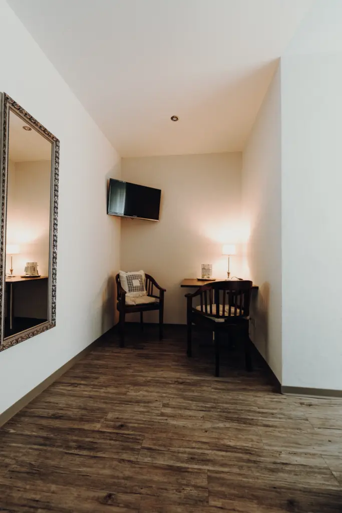 Schreibtisch mit Lampe und großem Wandspiegel im Hotelzimmer